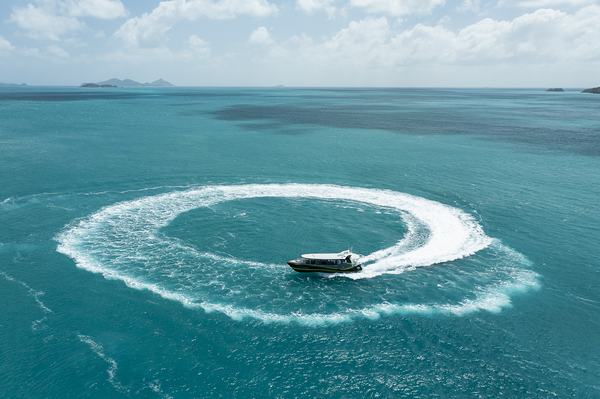a man riding a wave on top of a body of water with Lady Elliot Island in the background